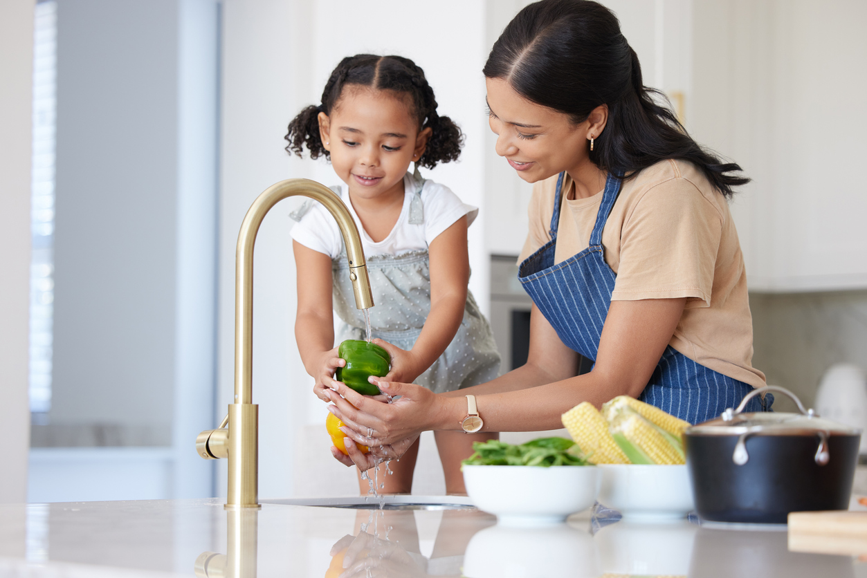 mom and daughter washing vegetables at kitchen sink