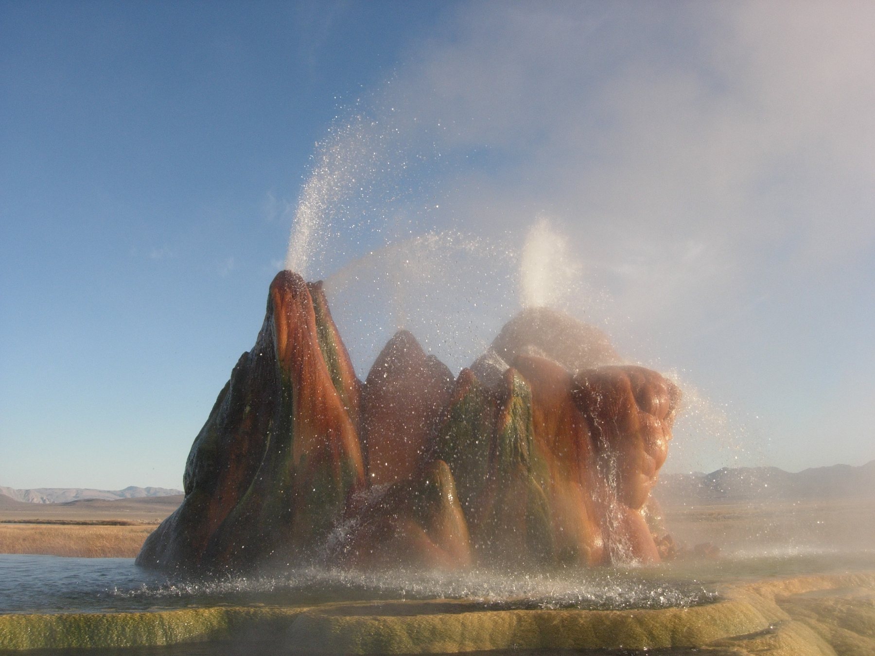 Colorful mineral terraces and steaming cones at Fly Ranch Geyser in the Nevada desert.