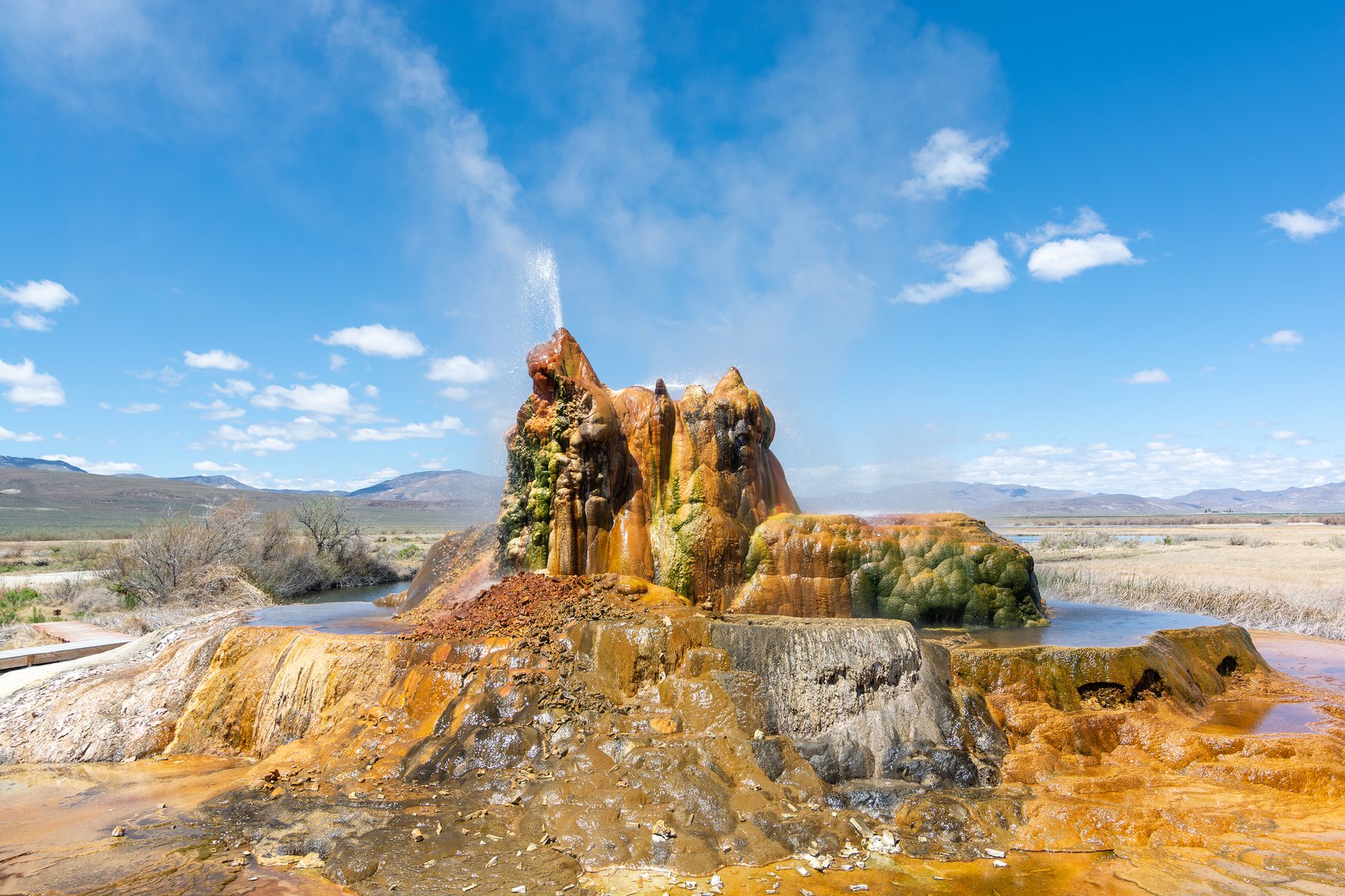 Fly Ranch Geyser rising from the high desert with mineral colors of orange, green, and gold.
