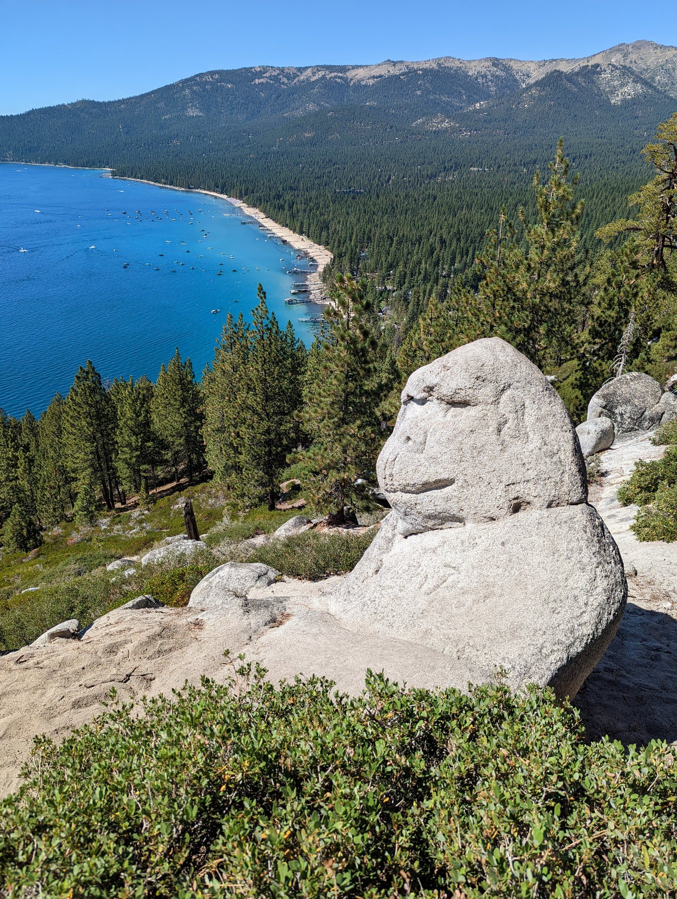 Granite Monkey Rock formation above Lake Tahoe with blue water visible below.