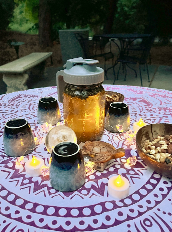 Tea and teacups on a colorful table cloth surrounded by twinkling lights, the final invitation of a forest therapy walk