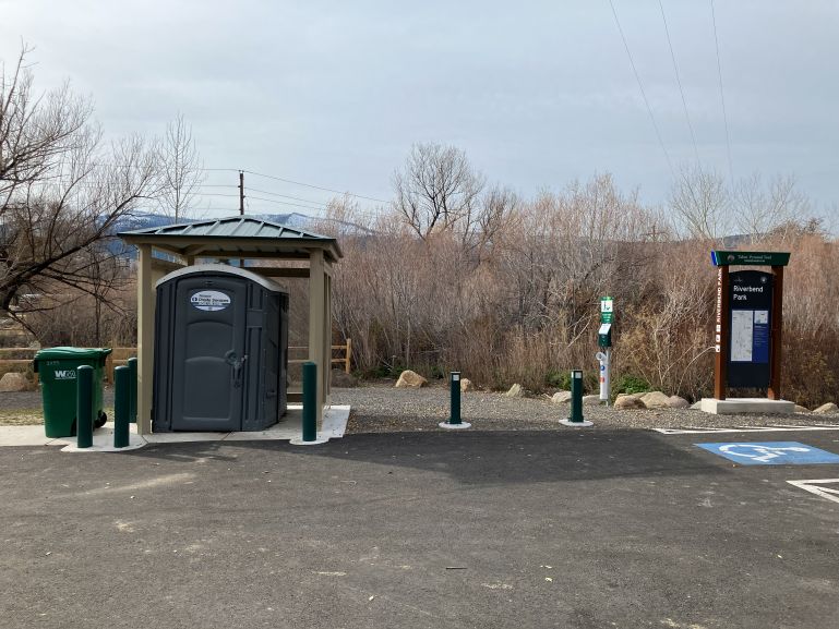 An accessible port-a-potty is connected to the paved parking area near designated handicap parking.